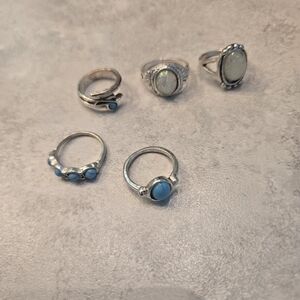 5 silver rings. 2 are opal and 3 are turquoise. Might be size 5 or 6.
